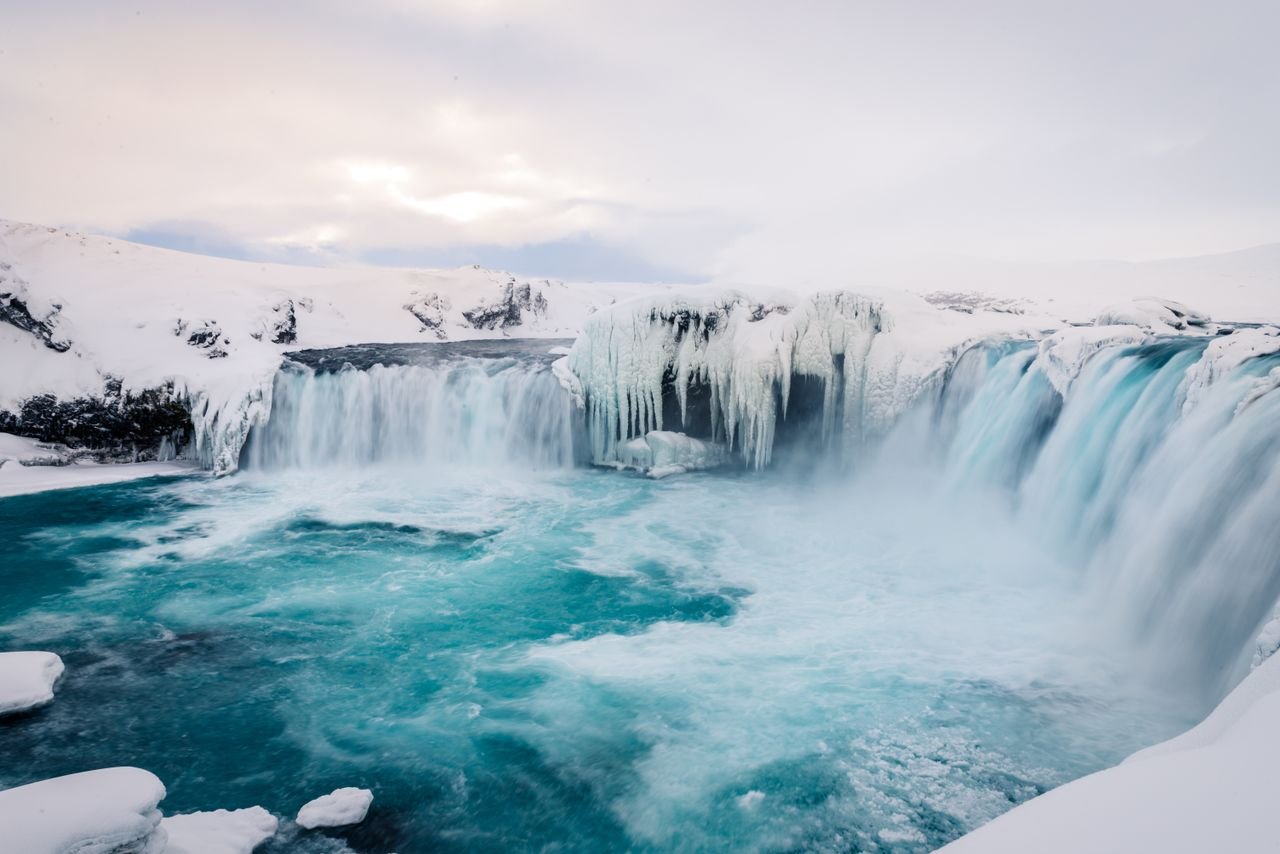 Breathtaking winter view of a frozen waterfall in Icelands snowy wilderness.